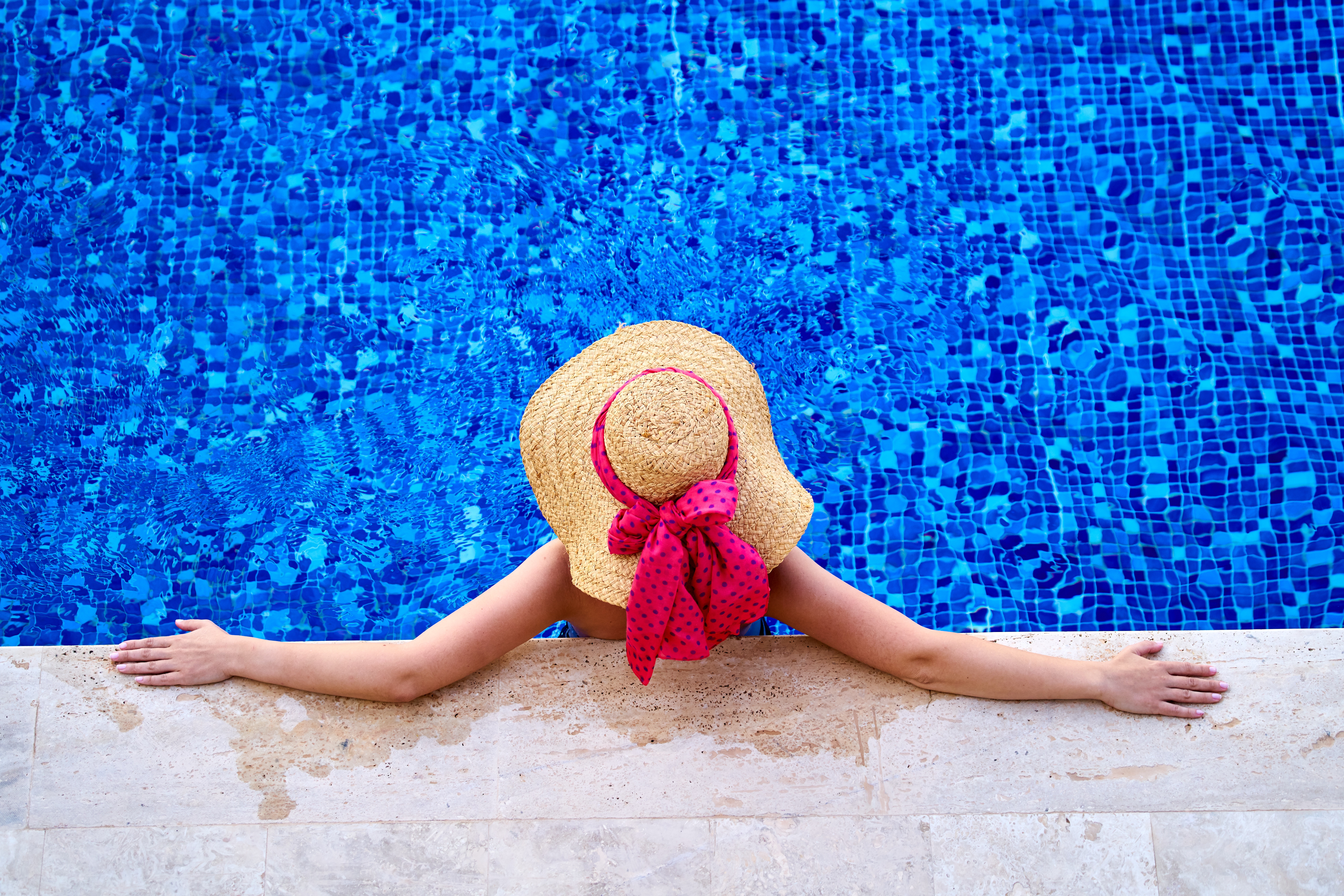 donna con cappello di paglia fiocco rosso in piscina